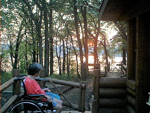Person in a wheel chair watching a sunset through a forest